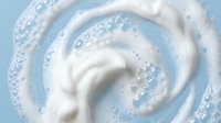Creamy white swirl with bubbles on light blue background for skincare cosmetics dairy products and fresh clean design concepts.