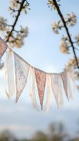 Vintage lace bunting hanging outdoors with soft spring blossoms in background creates romantic atmosphere for weddings, parties and celebrations.