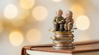 Senior couple figurines sitting on stack of golden coins with warm bokeh background representing retirement savings and financial security planning.