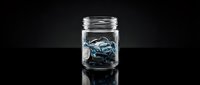 Glass jar filled with blue car keys on dark reflective surface for automotive dealership insurance concept storage organization.