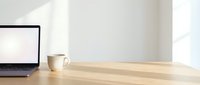 Clean minimalist workspace with laptop, coffee cup on wooden desk near bright window for productivity and remote work concepts.