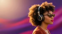 Young African American woman with curly afro hair wearing headphones and sunglasses against vibrant purple pink gradient background for music lifestyle content.