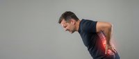 Middle-aged Caucasian man bending forward in pain, highlighted red spine area showing lower back injury on gray background.