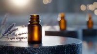 Amber glass essential oil bottle with fresh lavender sprigs on dark stone surface, soft bokeh background creates spa atmosphere. Natural aromatherapy concept.