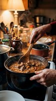 Senior chef stirring hearty beef stew in cast iron pot with wooden spoon in warm rustic kitchen during dinner preparation for comfort food cooking.