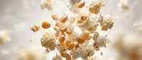 Flying popcorn kernels scattered in mid-air against soft blurred background creating dynamic motion effect for snack food advertising and cinema concepts.