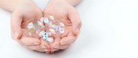 Female hands cupping colorful pills and capsules on white background. Healthcare, medicine, pharmaceutical concept for medical treatment and wellness.