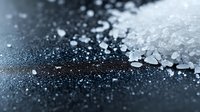 Scattered white salt crystals on dark background with dramatic lighting and shallow depth of field, creating abstract culinary composition.