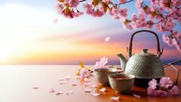 Traditional Japanese tea ceremony setup with cherry blossoms at sunset, featuring cast iron teapot and cups on wooden table for meditation and wellness.