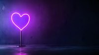Glowing purple neon heart shape on stand against dark background with misty floor reflection creates romantic atmosphere for Valentine's Day or love themes.