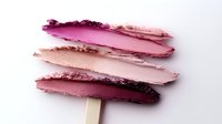 Cosmetic makeup swatches in various pink and purple tones on white background, showing texture and pigmentation of beauty products.