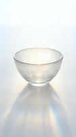 Frosted glass bowl on white surface casting rainbow light refraction, minimalist translucent cup with soft glow and prismatic shadow effect.