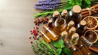 Essential oils in glass bottles with lavender, herbs and spices on wooden background for aromatherapy, natural wellness and holistic healing treatments.