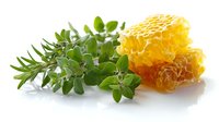 Fresh honeycomb piece with golden honey and green aromatic herbs on white background, natural organic food photography for healthy lifestyle and cooking.