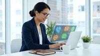 Professional Asian businesswoman working on laptop with digital communication icons in modern office environment. Remote work and technology concept.