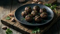 Homemade meatballs served on dark plate with fresh herbs on rustic wooden table. Traditional comfort food recipe for family dinner and cooking blogs.