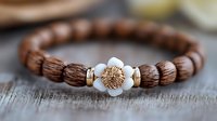 Handcrafted wooden bead bracelet with carved lotus flower centerpiece and white stone accent on rustic wooden surface, showcasing natural bohemian jewelry design.