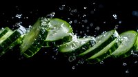 Fresh cucumber slices floating with water drops and splashes on black background, dynamic food photography composition for healthy eating and freshness concept.