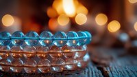 Luminous blue and pink crystal beads arranged in rows on rustic wooden surface with warm bokeh lights creating magical atmospheric background for spiritual concepts.