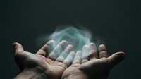 Hands releasing glowing turquoise powder or dust against dark background, symbolizing freedom, transformation, and letting go for wellness and spiritual concepts.