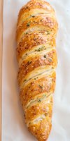 Golden braided puff pastry bread with herbs and sesame seeds on parchment paper for bakery menu and culinary projects.