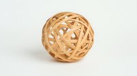 Woven bamboo decorative sphere on white background, natural eco-friendly home decor element with intricate pattern of intersecting strips. Isolated object for design use.