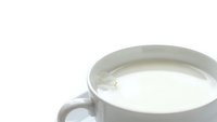 White ceramic cup filled with fresh milk on clean white background isolated for design projects and healthy beverage concepts.