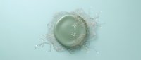 Sage green cosmetic cream with dynamic liquid splash effect on pale blue background, isolated for skincare product packaging and beauty design use.