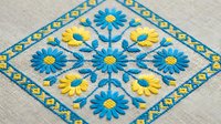 Traditional Ukrainian folk embroidery with blue and yellow floral motifs on natural linen fabric. Handcrafted needlework featuring geometric patterns.