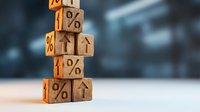 Wooden blocks stacked in a tower with percent signs and upward arrows, symbolizing rising interest rates and financial growth on a blurred background.