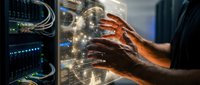 Technician with dark skin tone working on server hardware, hands touching illuminated circuit board connections in data center environment for IT support and network maintenance.