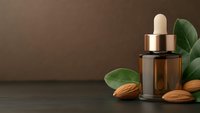 Amber glass dropper bottle with almond oil serum surrounded by fresh almonds and green leaves on dark wooden surface for natural skincare and wellness.