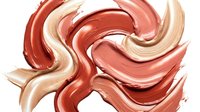 Swirled makeup foundation and concealer strokes in warm coral and nude tones creating flowing abstract pattern on white background for cosmetic design.