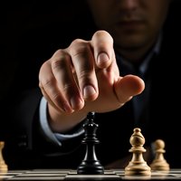 Business professional making strategic chess move with hand reaching toward black king piece on wooden chessboard in dramatic lighting.