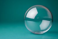Clear glass sphere on turquoise background with light reflections, showing transparency and minimalist composition for modern design and creative concepts.