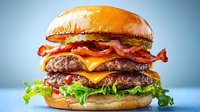 Double beef patties layered with crispy bacon, melted cheese, fresh lettuce on golden brioche bun against blue background, close up view of juicy burger.