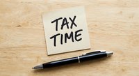 Tax time reminder note with black pen on wooden desk for accounting and financial planning preparation.