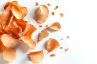 Scattered orange potato chips on white background, crispy curved snack pieces with natural texture and shadows, isolated food composition for packaging design.