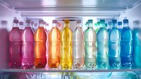 Colorful array of soft drinks in plastic bottles arranged in rainbow gradient order from pink to blue on refrigerator shelf, perfect for beverage industry marketing and healthy lifestyle concepts.
