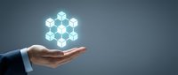 Businessman hand holding glowing hexagonal geometric network structure on gray background for technology, innovation, and digital transformation concepts.
