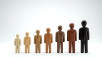 Wooden figures in increasing sizes representing human growth stages from child to adult on white background for business and development concepts.