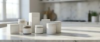 Minimalist white cosmetic containers and jars arranged on marble countertop in modern kitchen interior for skincare product mockup and branding.