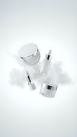 Luxury white and silver cosmetic set with serum dropper, lipstick, face cream jar, and powder compact on light background.