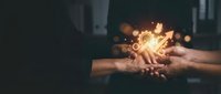Two hands holding glowing light bulb with sparkling energy effect, symbolizing innovation, creativity, ideas, and teamwork in business collaboration and problem-solving.