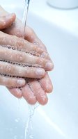 Clean water flowing through cupped hands with droplets and bubbles for hygiene and wellness concepts.