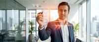 Professional businessman in modern office holding smartphone with glowing digital interface elements representing mobile technology and business innovation.