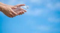 Male hand holding clear plastic water bottle against blue sky background, suitable for hydration, wellness, fitness, and environmental awareness campaigns.