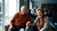 Happy senior Caucasian couple sitting together on couch at home, smiling elderly man and woman enjoying retirement lifestyle in comfortable living room.