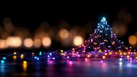 Colorful Christmas tree made from glowing LED string lights on dark surface with warm bokeh background creating festive holiday atmosphere.