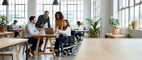 Diverse business team collaborating in modern office with wheelchair user promoting workplace inclusion and accessibility for corporate presentations.